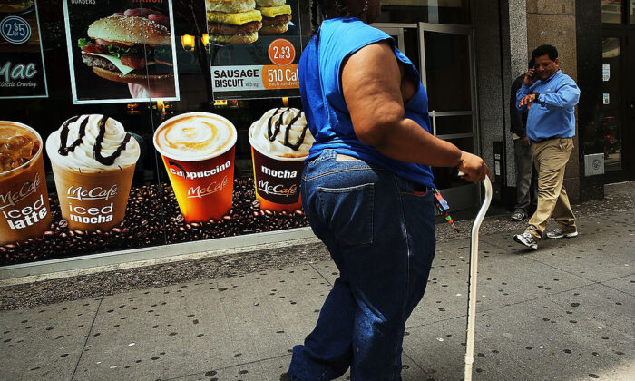 Una mujer pasa por un cartel que anuncia bebidas azucaradas en un barrio de Brooklyn con un alto índice de obesidad y diabetes el 11 de junio de 2013, en la ciudad de Nueva York. (Spencer Platt/Getty Images)
