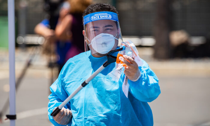 Un trabajador maneja una prueba de hisopado para COVID-19 en un sitio de pruebas en el Centro de Convenciones de Anaheim (California) el 15 de julio de 2020. (John Fredricks/The Epoch Times)