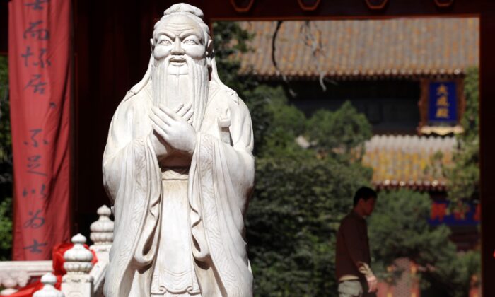 Un hombre camina junto a una estatua de Confucio en el Templo de Confucio en Beijing el 28 de septiembre de 2010. (LIU JIN/AFP vía Getty Images)
