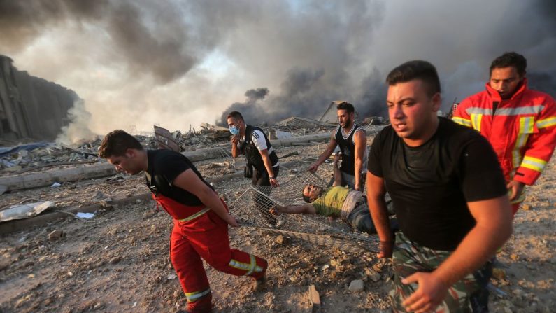 Los bomberos evacúan a un hombre herido del lugar de la explosión en el puerto de Beirut el 4 de agosto de 2020. (ANWAR AMRO/AFP vía Getty Images)