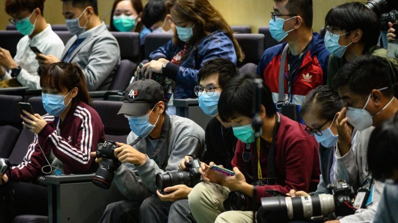 Periodistas con mascarillas se preparan antes de que la directora general de Hong Kong, Carrie Lam (no aparece en la foto), participara en una conferencia de prensa en Hong Kong el 25 de enero de 2020. (Foto de PHILIP FONG/AFP vía Getty Images)
