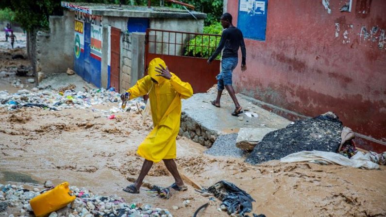 Personas caminan por una calle afectada por las intensas lluvias de la tormenta tropical Laura, el 23 de agosto de 2020 en Puerto Príncipe (Haití). EFE/Jeanty Emmanuel