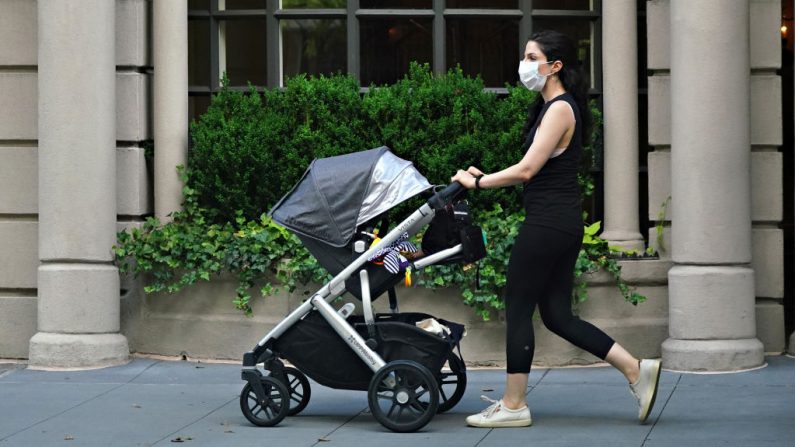 Imagen ilustrativa de una mujer con una máscara protectora empuja un cochecito, foto tomada el 13 de julio de 2020. (Foto de Cindy Ord/Getty Images)