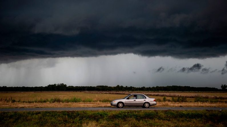 Un coche circula bajo una nube de lluvia ominosa de la tormenta tropical Marco mientras los lugareños se preparan para la llegada del huracán Laura cerca del lago Charles, Louisiana, el 25 de agosto de 2020. (Foto de ANDREW CABALLERO-REYNOLDS/AFP vía Getty Images)