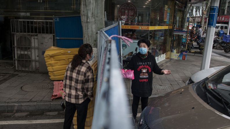 Dos residentes se comunican entre sí a ambos lados de una barricada improvisada construida para controlar la entrada y salida de un complejo residencial el 21 de abril de 2020 en Wuhan, provincia de Hubei, China. (Getty Images)