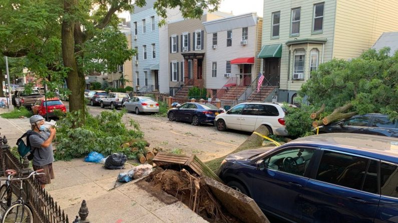 Un hombre toma fotos del daño causado por un árbol caído en el área de Greenpoint de Brooklyn, Nueva York, el 4 de agosto de 2020. (Foto de DIANE DESOBEAU/AFP vía Getty Images)