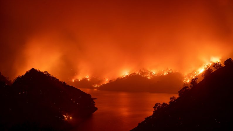 Las llamas rodean el lago Berryessa durante el incendio del LNU Lightning Complex en Napa, California, el 19 de agosto de 2020.- Miles de personas huyeron de sus hogares en el norte de California el 19 de agosto cuando cientos de incendios forestales de rápido movimiento se extendieron por la región, quemando casas y conduciendo a la muerte de un piloto de helicóptero. (JOSH EDELSON/AFP a través de Getty Images)