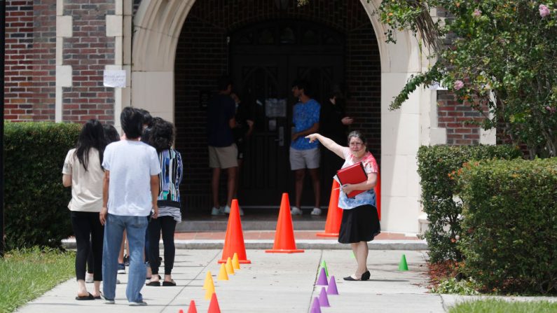 Una administradora de la Escuela Secundaria Hillsborough indica a los estudiantes donde recoger los ordenadores portátiles para el aprendizaje a distancia antes del primer día de clases del 21 de agosto de 2020 en Tampa, Florida (EE.UU.) (Octavio Jones/Getty Images)