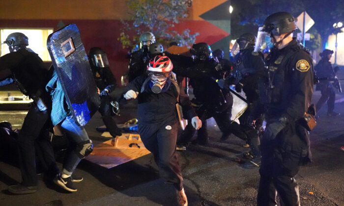 Alborotadores enfrentan a la policía de Portland, Oregon, Estados Unidos, mientras ellos dispersan a una multitud reunida frente a la comisaría norte de la Oficina de Policía la madrugada del 22 de agosto de 2020. (Nathan Howard/Getty Images)
