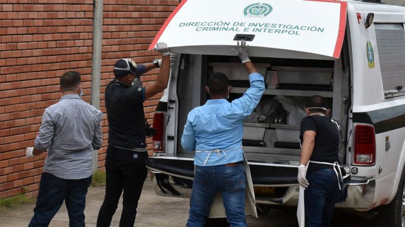 Miembros de la policía descargan los cuerpos de las víctimas de una masacre supuestamente a manos de un grupo armado en el municipio colombiano de Arauca, en la morgue de Arauca, cerca de la frontera con Venezuela, el 22 de agosto de 2020. (Foto de DANIEL FERNANDO MARTÍNEZ/AFP vía Getty Images)