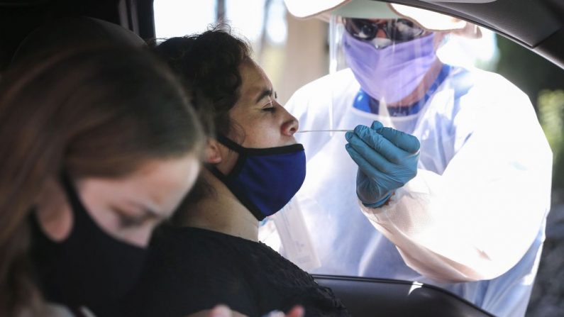 Una trabajadora de la salud ayuda a una automovilista con una prueba de hisopado nasal en un centro de pruebas de coronavirus (COVID-19) el 11 de agosto de 2020 en Los Ángeles, California. (Mario Tama/Getty Images)
