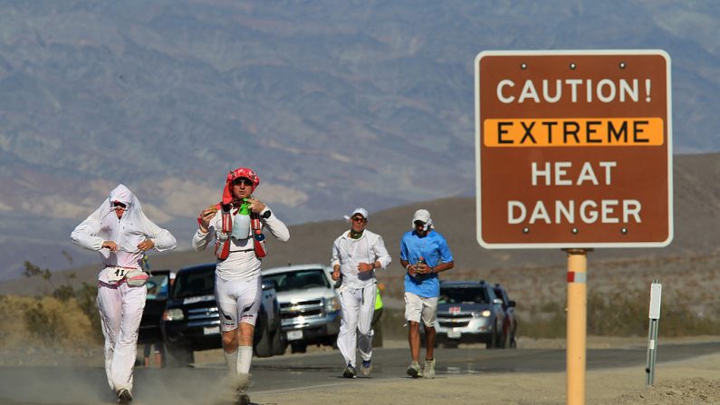 Los corredores pasan una señal de advertencia de peligro de calor durante la carrera de ultramaratón AdventurCORPS Badwater 135 el 15 de julio de 2013 en el Parque Nacional de Death Valley, California (EE.UU.). (Foto de David McNew/Getty Images)