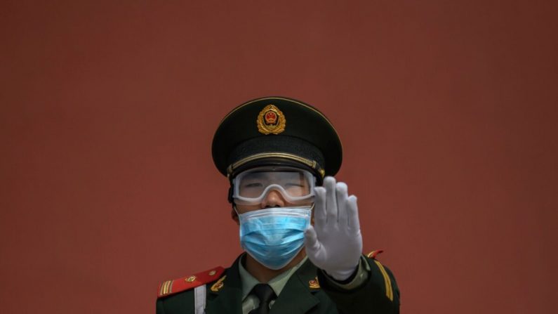 Un oficial de policía paramilitar chino con mascarilla hace un gesto mientras hace guardia en la entrada de la Ciudad Prohibida el 1 de mayo de 2020. (Kevin Frayer/Getty Images)