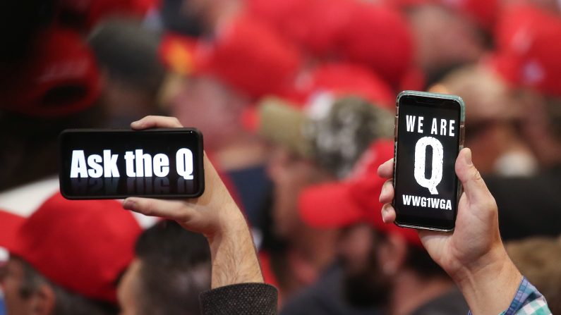 La gente sostiene teléfonos inteligentes con mensajes relacionados con QAnon, en un mitin en Las Vegas, Nev., el 21 de febrero de 2020. (Mario Tama/Getty Images)
