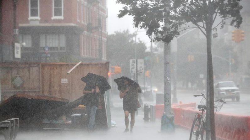 Dos personas caminan por las calles de Nueva York, azotadas por el viento causado por la tormenta tropical Isaías, el 4 de agosto de 2020. EFE/Jason Szenes