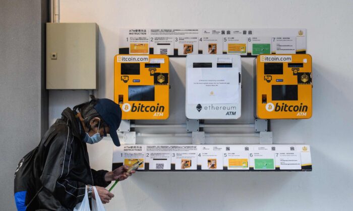 Un hombre usa su teléfono mientras pasa frente a los cajeros automáticos de la moneda digital Bitcoin, en Hong Kong, el 18 de diciembre de 2017. (Anthony Wallace/AFP a través de Getty Images).