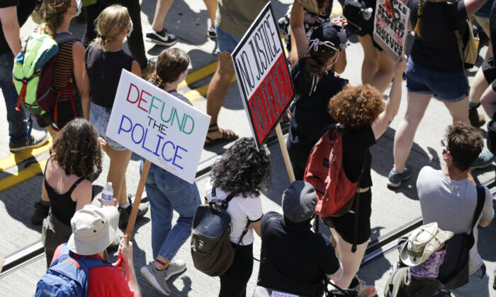 La gente lleva carteles durante la marcha "Desfinanciar la policía" desde la cárcel juvenil del condado de King hasta el ayuntamiento de Seattle, Washington, el 5 de agosto de 2020. (Jason Redmond/AFP vía Getty Images)