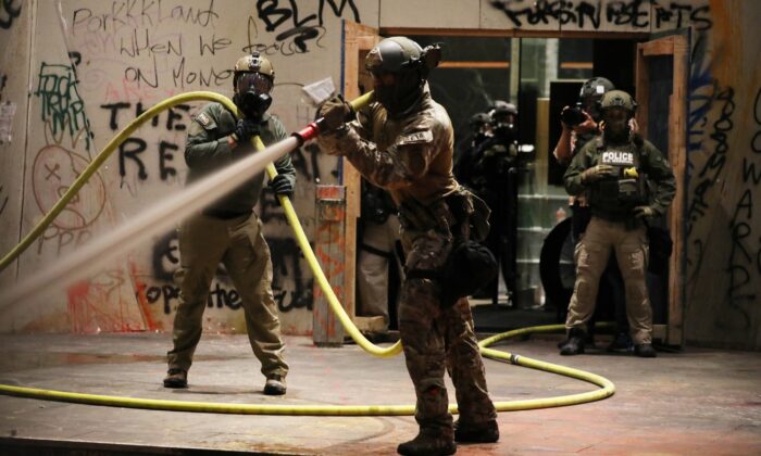 La policía federal limpia las proximidades del tribunal federal Mark O. Hatfield en el centro de Portland mientras la ciudad experimenta otra noche de disturbios, en Portland, Ore., el 28 de julio de 2020. (Spencer Platt/Getty Images)