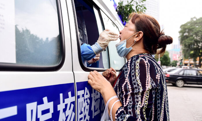 Un trabajador de salud realiza una prueba COVID-19 en un residente en un vehículo de prueba en Shenyang, en la provincia de Liaoning, noreste de China, el 29 de julio de 2020. (STR/AFP a través de Getty Images)