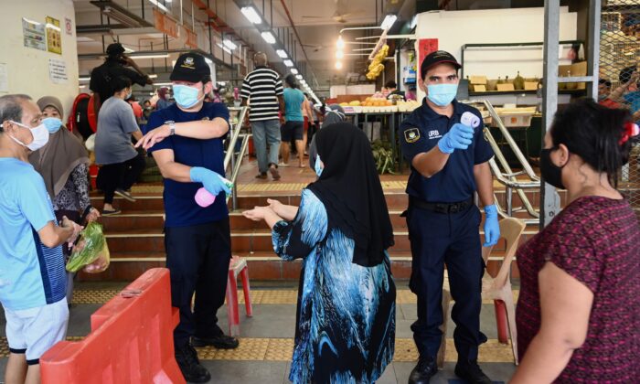El personal de seguridad revisa la temperatura de las personas que entran en un mercado, al mismo tiempo que aplican el distanciamiento social, en Penang, Malasia, el 29 de mayo de 2020. (Goh Chai Hin/AFP vía Getty Images)