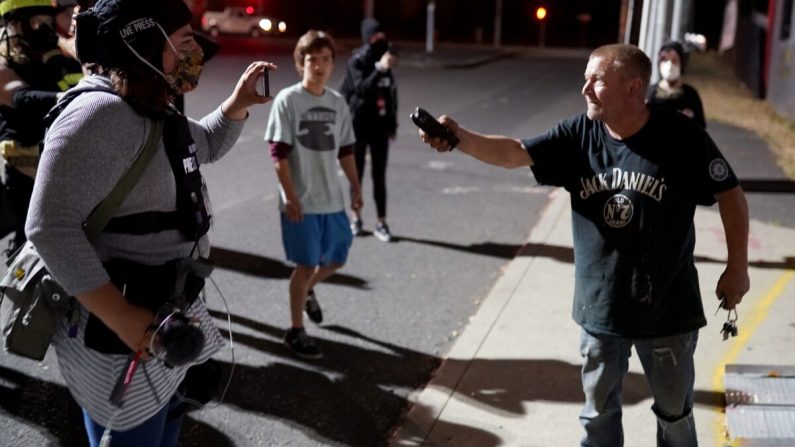 Un hombre empuña un arma aturdidora durante una discusión con los manifestantes después de que se dirigieron a su negocio en el barrio South Waterfront en Portland, Ore., el 20 de agosto de 2020. (Nathan Howard/Getty Images)