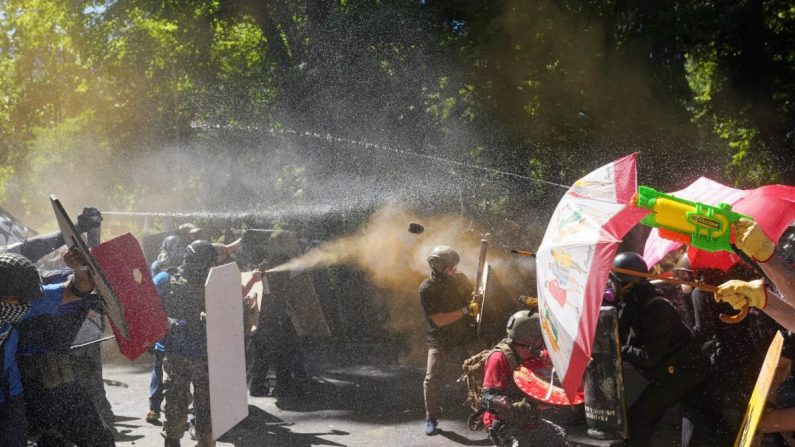 Los manifestantes a favor de la policía y otros (izq.) y contramanifestantes, disparan gas pimienta y se arrojan objetos frente al Centro de Justicia del Condado de Multnomah en Portland, Oregón, el 22 de agosto de 2020. (Nathan Howard/Getty Images)