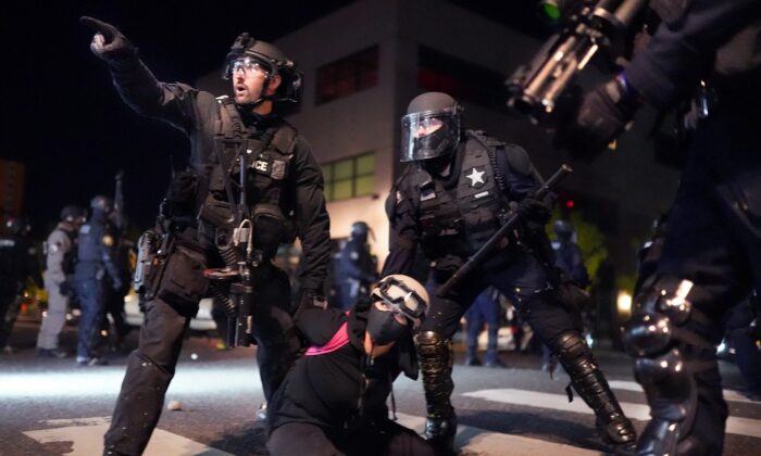 La policía de Portland y la patrulla estatal de Oregon trabajan juntos para arrestar a un manifestante frente a la comisaría norte de la policía de Portland en el 75º día de protestas y disturbios, en Portland, Oregón, el 11 de agosto de 2020. (Nathan Howard/Getty Images)
