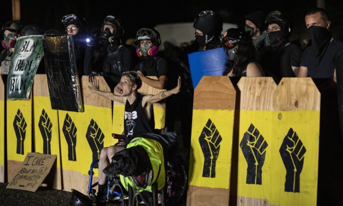 Una mujer grita a la policía mientras los manifestantes sostienen carteles con el símbolo Black Lives Matter en Portland, Oregon, el 15 de agosto de 2020 (Paula Bronstein/Getty Images)
