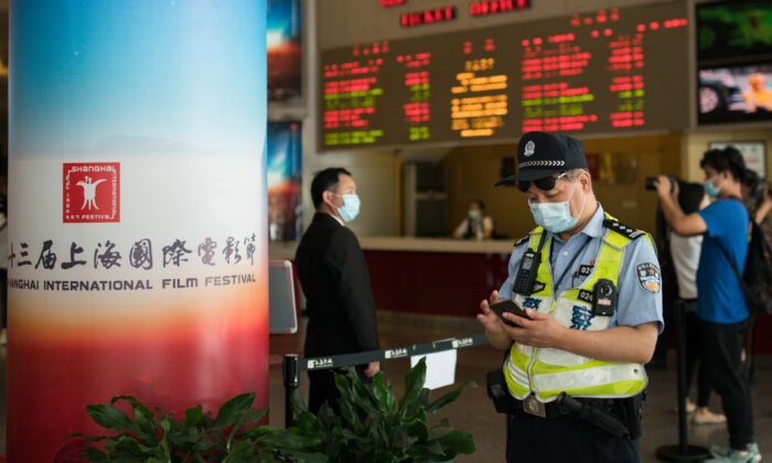 Un policía mira su celular en el Shanghái Film Center (SFC) en Shanghái el 25 de julio de 2020. (Yifan Ding/Getty Images)