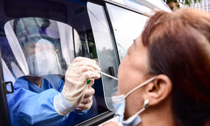 Un trabajador de la salud realiza una prueba de coronavirus COVID-19 a un residente desde un vehículo en Shenyang, en la provincia nororiental de Liaoning, China, el 29 de julio de 2020. (STR/AFP vía Getty Images)