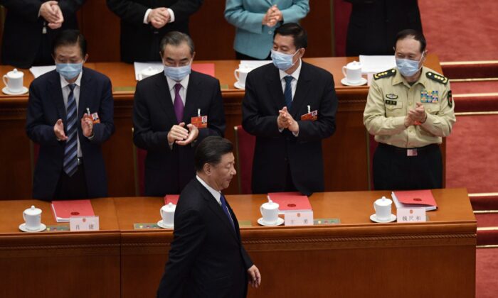 El líder chino Xi Jinping es aplaudido por altos funcionarios cuando llega a la sesión de clausura de la conferencia legislativa del régimen en el Gran Salón del Pueblo de Beijing, el 28 de mayo de 2020. (NICOLAS ASFOURI/AFP vía Getty Images)