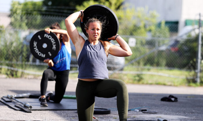 Una mujer sostiene una pesa sobre su cabeza durante un entrenamiento físico al aire libre debido a que se ordenó el cierre de los gimnasios interiores, en Oceanside, Nueva York, el 20 de julio de 2020. (Al Bello/Getty Images)