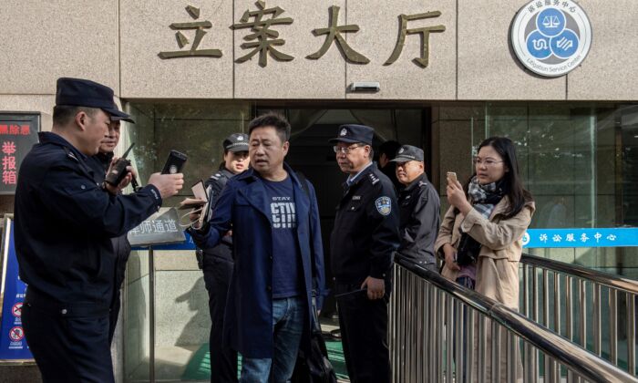 El abogado Xie Yang (centro) acompañó a su cliente Xu Yan (derecha), esposa del abogado de derechos humanos Yu Wensheng, están tratando de reunirse con Yu en persona fuera de la Corte Intermedia de Xuzhou en Xuzhou en la provincia de Jiangsu en el este de China el 31 de octubre de 2019.  (NICOLAS ASFOURI/AFP vía Getty Images)