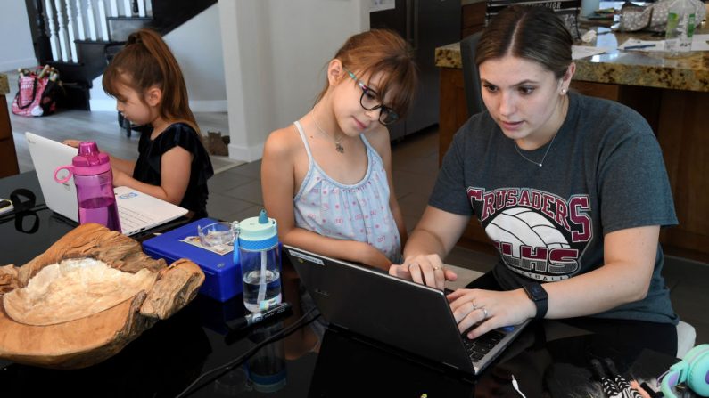 Ella Dweck (i) y Odette Conrad (c), de 7 años, toman una clase en línea en casa con la ayuda de Jordyn Leal (d), estudiante del Colegio del Sur de Nevada, durante la primera semana de aprendizaje a distancia para el Distrito Escolar del Condado de Clark en medio de la propagación del COVID-19 el 25 de agosto de 2020 en Las Vegas, Nevada (EE.UU.). (Foto de Ethan Miller/Getty Images)