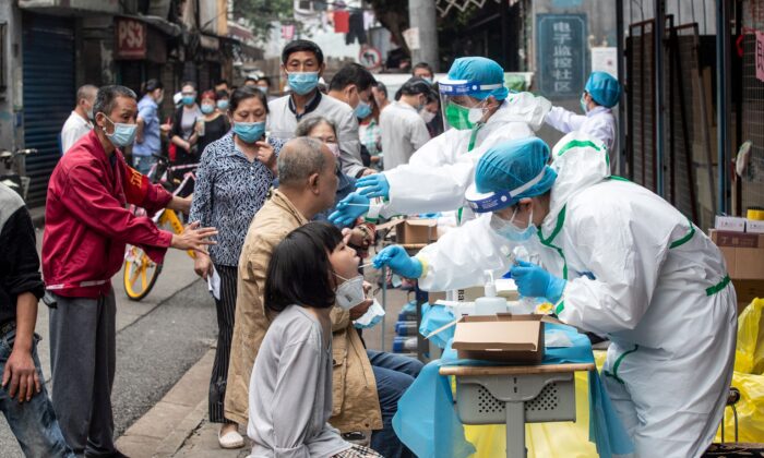 Trabajadores de la salud realizan los test de coronavirus COVID-19 en una calle de Wuhan en la provincia central de Hubei en China el 15 de mayo de 2020. (STR/AFP vía Getty Images)