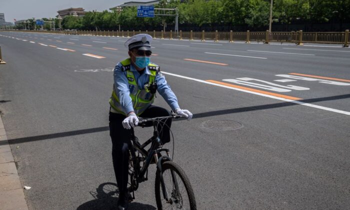 Un oficial de policía se desplaza en bicicleta, en Beijing, el 18 de mayo de 2020. (Nicolas Asfouri/AFP a través de Getty Images).