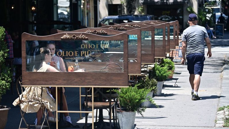 Clientes se sientan fuera de un restaurante, que tiene ventanas instaladas entre las mesas cuando la ciudad de Nueva York entra en la segunda fase de reapertura el 22 de junio de 2020. (Johannes Elisele/AFP vía Getty Images)
