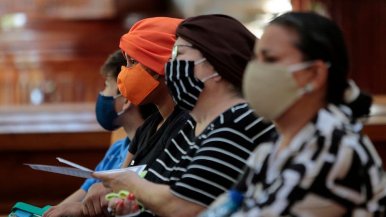 Personas con mascarillas para prevenir la propagación del COVID-19 rezan en la Catedral de Managua, reabierta después de varios días de cierre debido a un incendio que quemó la imagen de la "Sangre de Cristo", en Managua (Nicaragua), el 6 de agosto de 2020. (Foto de INTI OCON/AFP vía Getty Images)