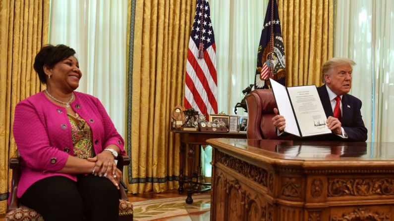 El presidente de Estados Unidos Donald Trump muestra el indulto completo de Alice Johnson en la Oficina Oval de la Casa Blanca en Washington, D. C., el 28 de agosto de 2020. (Foto de NICHOLAS KAMM/AFP a través de Getty Images)