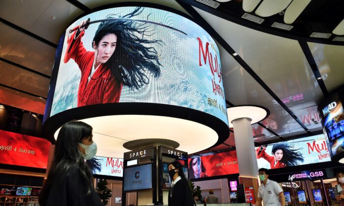 La gente pasa frente a las pantallas publicitarias de la película Mulan de Disney en un cine dentro de un centro comercial en Bangkok el 8 de septiembre de 2020 (Lillian Suwanrumpha / AFP a través de Getty Images).