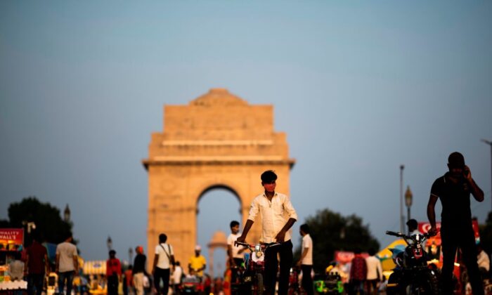 Un vendedor (centro) que lleva una mascarilla busca clientes para que monten en su bicicleta de juguete por la calle Rajpath, cerca de la Puerta de la India en Nueva Delhi, el 16 de septiembre de 2020. (Jewel Samad/AFP a través de Getty Images).