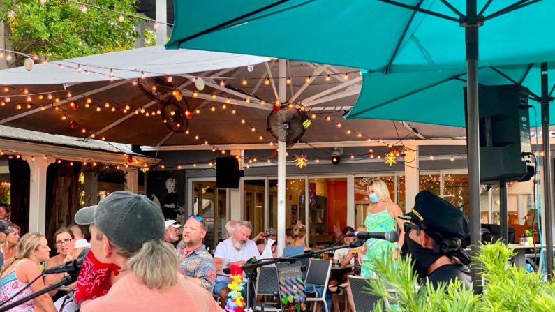 Cantantes con mascarillas actúan en el área de comedor al aire libre de un restaurante en Key West, Florida el 17 de septiembre de 2020 en medio de la pandemia de COVID-19. (Foto de DANIEL SLIM/AFP vía Getty Images)