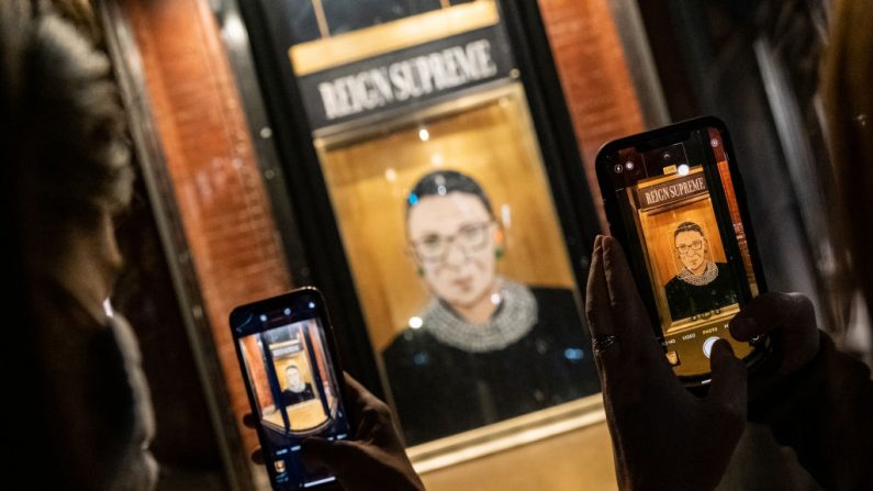 La gente toma una foto de un retrato de la jueza de la Corte Suprema Ruth Bader Ginsburg exhibido en un escaparate el 19 de septiembre de 2020 en Nueva York, Nueva York. Ginsburg falleció a la edad de 87 años después de una batalla contra el cáncer de páncreas. (Jeenah Moon/Getty Images)