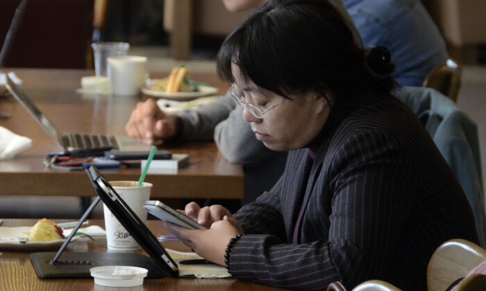Una mujer lee su teléfono y su tableta en un café en Beijing, el 2 de noviembre de 2012. (WANG ZHAO/AFP vía Getty Images)