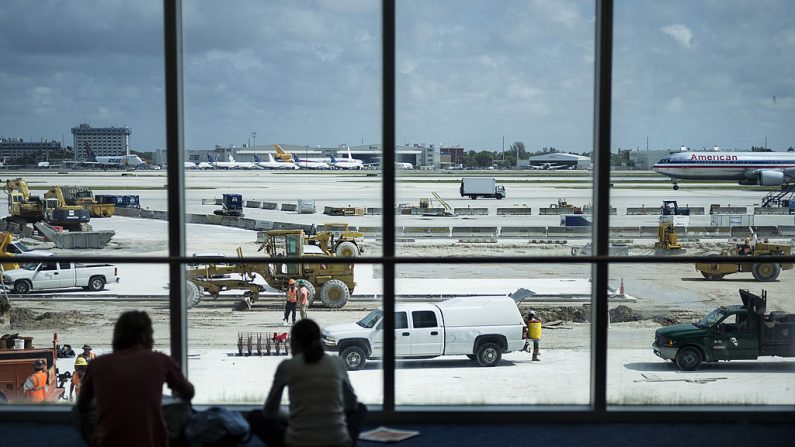 Viajeros observan como los trabajadores construyen una puerta en el Aeropuerto Internacional de Miami el 10 de junio de 2013 en Miami, Florida. (Brendan Smialowski/AFP vía Getty Images)