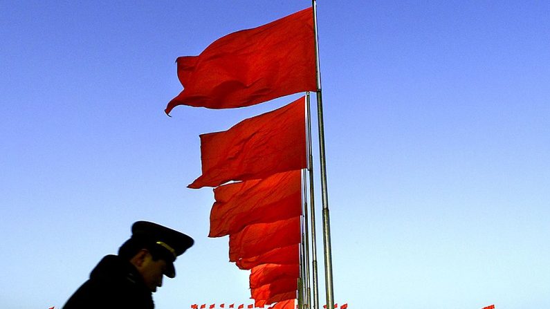 El Gran Salón del Pueblo (al fondo) por la mañana cuando un policía chino patrulla la plaza Tiananmen, en Beijing el 06 de marzo de 2000. (STEPHEN SHAVER/AFP vía Getty Images)