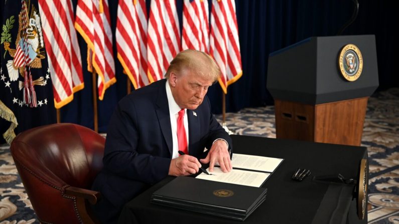 El presidente Donald Trump firma órdenes ejecutivas que extienden la ayuda económica por el virus del PCCh, durante una conferencia de prensa en Bedminster, Nueva Jersey, el 8 de agosto de 2020. (Jim Watson/AFP vía Getty Images)