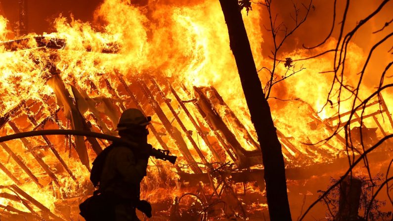 Un bombero de Cal Fire monitorea una casa en llamas mientras el Campamento de Bomberos se mueve a través del área  en Magalia, California.  (Justin Sullivan vía Getty Images)