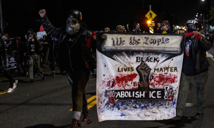 Dos personas llevan una pancarta durante una marcha que se convirtió en revuelta en Portland, Oregon, el 5 de septiembre de 2020. (Allison Dinner/AFP vía Getty Images)