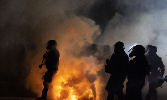 Los agentes del estado de Oregón y la policía de Portland avanzan a través de gases lacrimógenos mientras se enfrentan a los alborotadores en Portland, Oregón, el 5 de septiembre de 2020. (Nathan Howard/Getty Images).